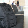 Gruv Gear Club Bag Tech Backpack in Stealth Elite Triple Black on bench in airport lounge